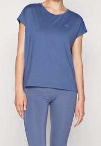 Blue short-sleeve athletic top made of lightweight fabric, featuring a round neck and a relaxed fit, paired with matching blue leggings.