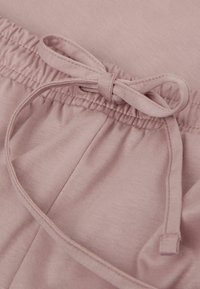 Lichtroze katoenen shorts met een elastische tailleband en een strikdetail. Gladde textuur, lichte glans en geplooid ontwerp bij de taille.