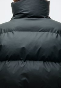 Sort dunjakke med høj krave, quiltede sektioner og en glat, blank overflade, der giver isolering og et moderne design.