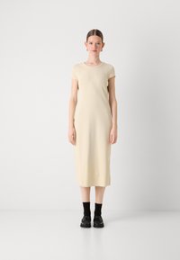 Cream cotton midi dress with short sleeves and a round neckline, worn with black shoes and ankle socks. Smooth texture, simple design.