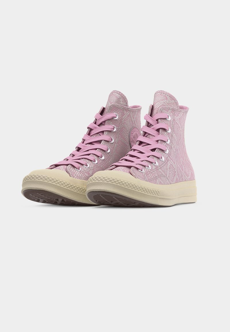 Roze sneakers met een hoge schacht en een slangenhuidpatroon, crèmekleurige zolen en bijpassende roze veters op een witte achtergrond.