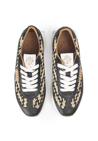 Zapatillas negras y beige con diseño de tejido trenzado, cordones blancos y suela acolchada. Etiqueta del logo en el lateral con detalles en dorado.