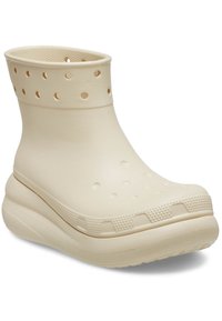 Bottine beige en caoutchouc avec tige perforée, semelle intérieure texturée et plateforme épaisse. Bout arrondi et finition lisse.