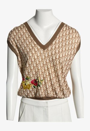 Haut en maille sans manches beige et marron avec col en V, motif monogramme, et fleurs rouges et jaunes brodées sur le côté.