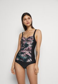 Schwarzer einteiliger Badeanzug mit einem bunten tropischen Blattmuster auf der Vorderseite und einfarbigen schwarzen Seiten. Dünne Träger und ein gerafftes Brustdetail.