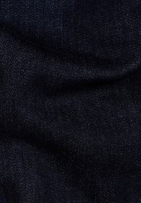 Tercio de denim oscuro con una superficie lisa y ligeramente texturizada. Presenta variaciones sutiles en el color y patrones de tejido en diagonal tenues.