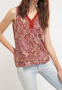 Top senza maniche con motivo paisley in rosso e beige, con scollatura a V e dettagli testurizzati. Tessuto leggero, vestibilità comoda.