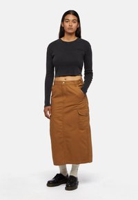 Gonna cargo in cotone marrone con tasche laterali, abbinata a un top fitted a maniche lunghe nero a costine. Scarpe nere e calze crema completano il look.