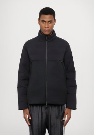 Puffer jacket in black, with a high collar and a zip closure. Features a two-tone design with a smooth upper and textured lower section.