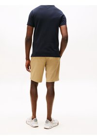 Laivastansiniset polo-paidat ja khaki-shortsit. Paidassa on lyhyet hihat; shortsit ovat rentoja ja suoralla leikkauksella. Urheilukengät, joissa on valkoisia ja harmaita yksityiskohtia.