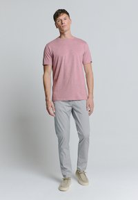 Roze heide korte mouwen T-shirt, grijze slim-fit broek, lichtbeige schoenen. Eenvoudig ontwerp met een ronde halslijn en geen opvallende patronen.
