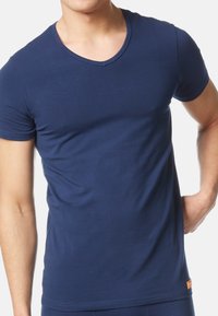 Marineblå kortærmet T-shirt med rund hals. Fremstillet af blødt stof, har en slim fit og et orange logo-tag nederst til venstre.