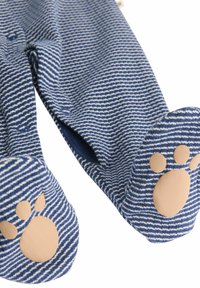 Pigiama con piedi a righe marine realizzato in tessuto morbido, con dettagli di impronte di zampe sulle suole e cuciture di colori chiari.