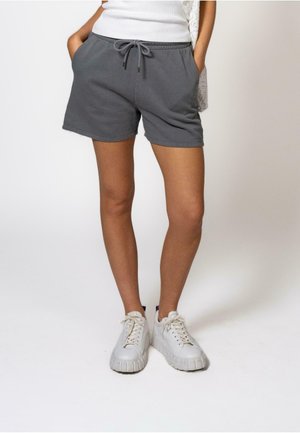Shorts gris en mélange de coton avec une taille élastique à cordon, poches latérales et une coupe décontractée, associés à des baskets blanches.