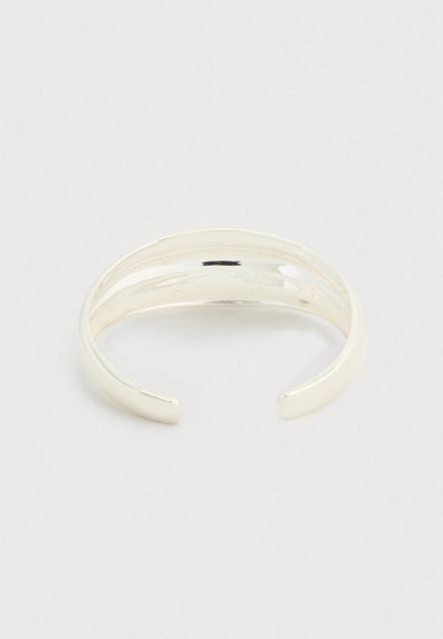 Ασημένιο βραχιόλι με εφέ γυαλισμένης, λείου φινιρίσματος. Διαθέτει ανοιχτό σχεδιασμό με στρογγυλεμένες άκρες και μινιμαλιστικό στυλ.