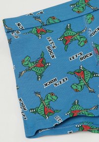 Modré látkové pánské boxerkové kraťasy se opakujícím vzorem zelených kreslených dinosaurů, kteří nosí sluneční brýle a hrají na elektrickou kytaru, s textem "POJĎME ROCKOVAT."