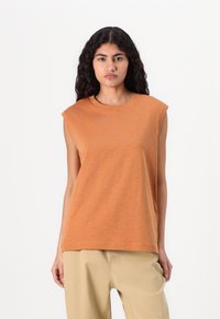T-shirt sans manches orange en tissu doux avec un col rond et une coupe décontractée, présentant une texture subtile et sans accents visibles.