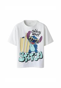 T-shirt bianco a maniche corte con una grafica colorata di un personaggio blu con occhiali da sole, con il testo "Catching Waves" e "STITCH."