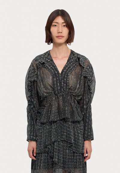 Haut transparent noir et argent à motifs, avec des accents volants, un décolleté en V profond et des manches longues. Conception légère et superposée avec un tissu texturé.