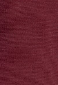 Tessuto a maglia bordeaux con una superficie morbida e testurizzata, caratterizzato da un pattern uniforme di fili sottili intrecciati.