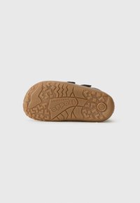 Suola della scarpa realizzata in un robusto materiale in gomma marrone, dotata di scanalature profonde per una maggiore aderenza e un logo impresso al centro.