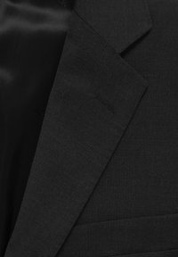 Zwarte blazer met een gladde satijnen voering, notch-kraag en gestructureerde stof. Inclusief subtiele branding aan de binnenkant.