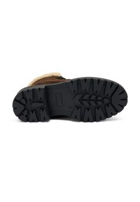 Bota marrón con una suela de goma negra texturizada, que presenta un patrón de banda de rodadura prominente y un forro blanco esponjoso a lo largo de la abertura.