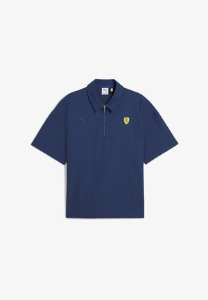 Tengerészkék, rövid ujjú póló felső, cipzáras gallérral, arany Puma logóval és Ferrari címerrel a bal mellen.