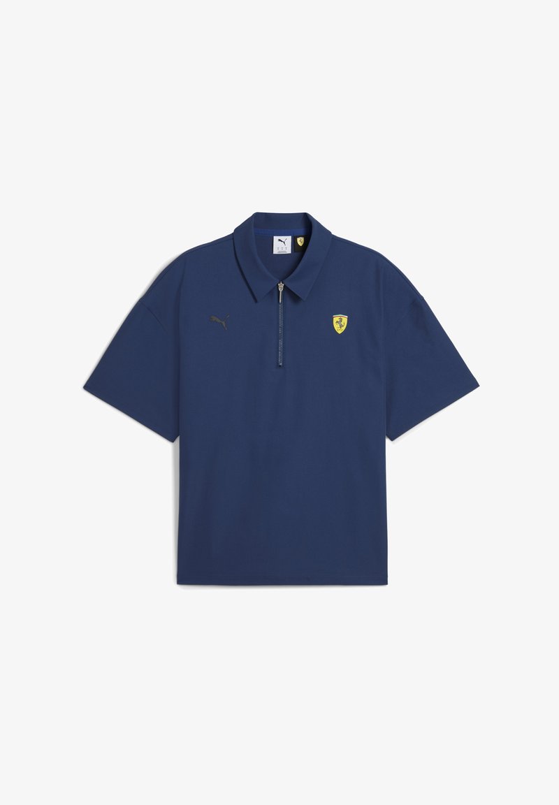 Mornarsko modra polo majica s kratkimi rokavi in zapenjanjem pri ovratniku, ki vsebuje zlati logotip Puma in grb Ferrarija na levi strani prsnega dela.