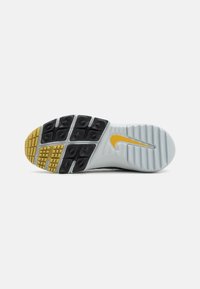 Nike sporta apavu zole, kas veidota no baltas un gaiši pelēkas gumijas ar melniem saķeres elementiem un dzeltena Nike swoosh akcentu.
