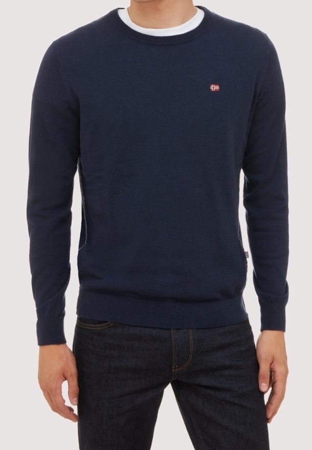 Pull ras du cou bleu marine en tissu tricoté doux, avec un petit logo rouge et blanc sur la poitrine, et des poignets et un ourlet côtelés.