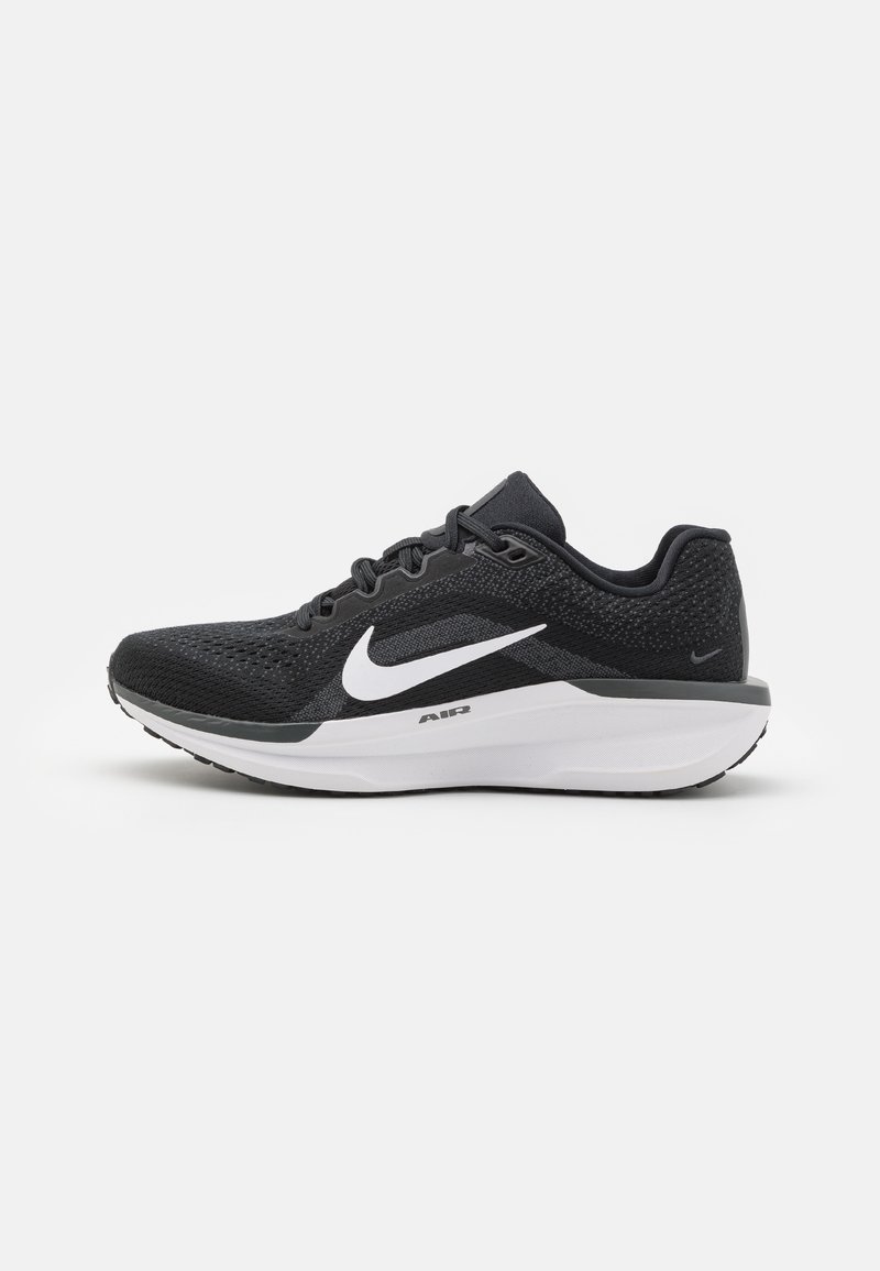Schwarzer Sportschuh mit einem Mesh-Obermaterial, weißem Nike-Swoosh und gepolsterter Sohle. Verfügt über Schnürsenkel und eine strukturierte Rückseite für Stabilität.