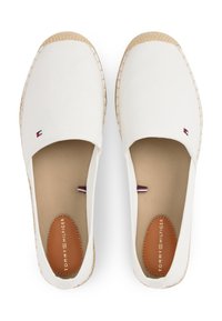 Espadrilles en toile blanche avec une semelle en jute. Présentent un petit logo en bleu, rouge et blanc au niveau de l'orteil. Doublure intérieure lisse de couleur tan.