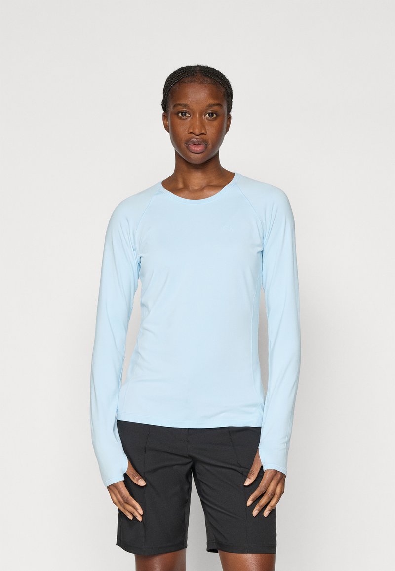 Jasnoniebieska koszula z długim rękawem wykonana z gładkiego, elastycznego materiału, z okrągłym dekoltem i rękawami raglanowymi, w zestawie z czarnymi szortami.