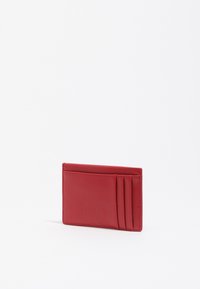 Tarjetero de cuero rojo con textura suave, seis ranuras para tarjetas y un logotipo en relieve en la parte frontal. Diseño compacto y minimalista.