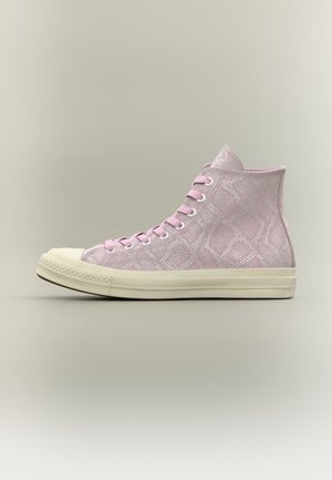 Zapatilla alta con estampado de serpiente en rosa, cordones rosas y suela y puntera de goma en color crema sobre fondo neutro.