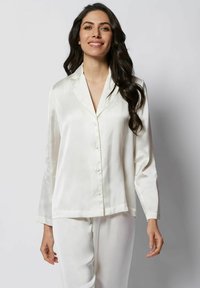 Set de pijama din satin alb, format dintr-o cămașă cu nasturi, cu guler în V și mâneci lungi, completat cu pantaloni drepti asortați.