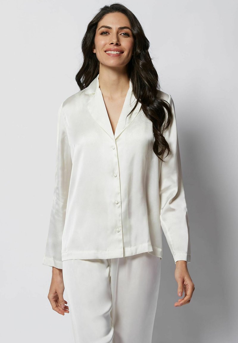 Set de pijama din satin alb, format dintr-o cămașă cu nasturi, cu guler în V și mâneci lungi, completat cu pantaloni drepti asortați.