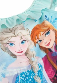 Costume da bagno con uno sfondo blu chiaro, spalline arricciate e illustrazioni di due personaggi con acconciature e abbigliamento distintivi.