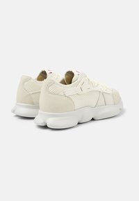 Sneaker bianche con materiali in rete e suede, suola arrotondata, design con lacci e sottili accenti rossi sulla linguetta.