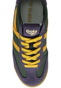 Zapatilla Gola con cordones amarillos, franjas laterales amarillas, acentos de ante morado, tela verde oscura, y el logo "Gola" en la lengüeta y en la plantilla.