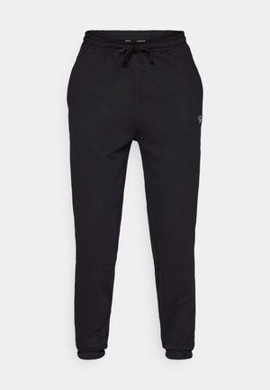 Pantaloni della tuta neri realizzati in tessuto morbido, con vita elasticizzata e coulisse, gambe affusolate e un piccolo dettaglio del logo sul lato.
