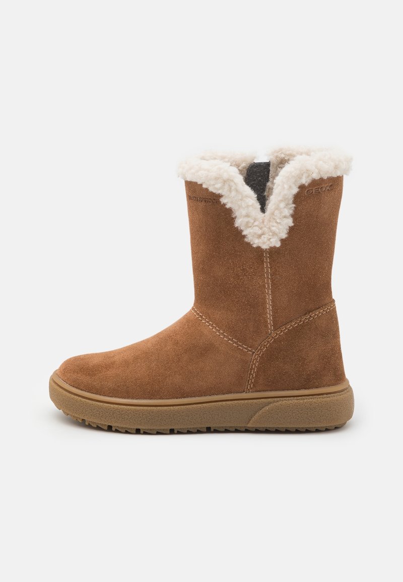 Botte d'hiver en daim marron avec doublure en shearling crème et semelle en caoutchouc texturée, hauteur mi-mollet, vue latérale sur fond blanc.