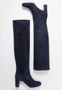 Stivali alti in suede blu navy con tacco a blocco, texture liscia e design aderente. Presentano una punta arrotondata e dettagli di cucitura minimi.