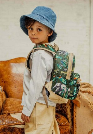Groene rugzak met een patroon van dieren, beige accenten en verstelbare schouderbanden, gedragen door een kind in een licht shirt en een spijkermuts.