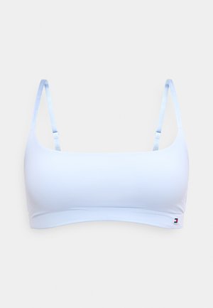 Brassière courte bleu clair sans coutures avec bretelles fines réglables et petit patch logo rouge, blanc et bleu sur la bande inférieure droite.