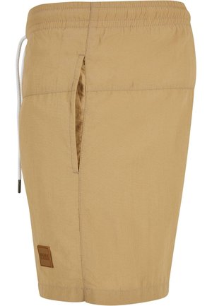 Shorts de bain beiges en tissu léger, dotés d'une poche latérale, d'une taille élastique et d'un cordon de serrage avec une étiquette logo rectangulaire.