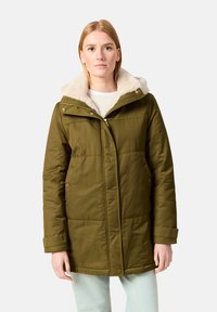 Parka aislante en verde oliva con capucha forrada de piel sintética, cierre frontal con cremallera y bolsillos laterales. Presenta una textura acolchada y detalles de botones.