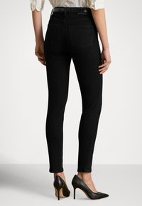 Sorte, tettsittende jeans med høy midje, to baklommer og glatt, elastisk denim. Brukes med svarte spisse høye hæler.