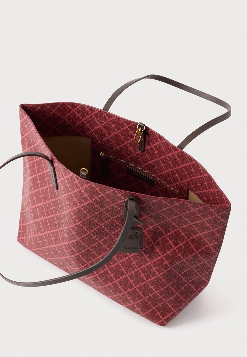 Rote Tragetasche mit Muster, braunen Ledergriffen, klar strukturierter Form und Innenreißverschlusstasche. Auffälliges Kreuzschraffur-Design auf der Außenseite.